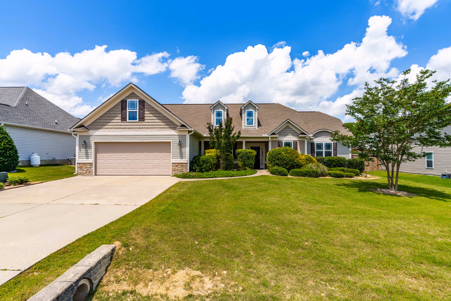 Front exterior view of Miss Bell’s Assisted Living of Garner with a two-car garage and lawn.