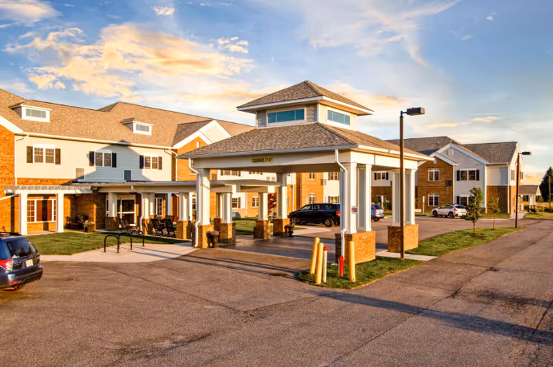 Exterior view of English Meadows Stephens City Campus featuring entrance porte-cochere and parked cars.