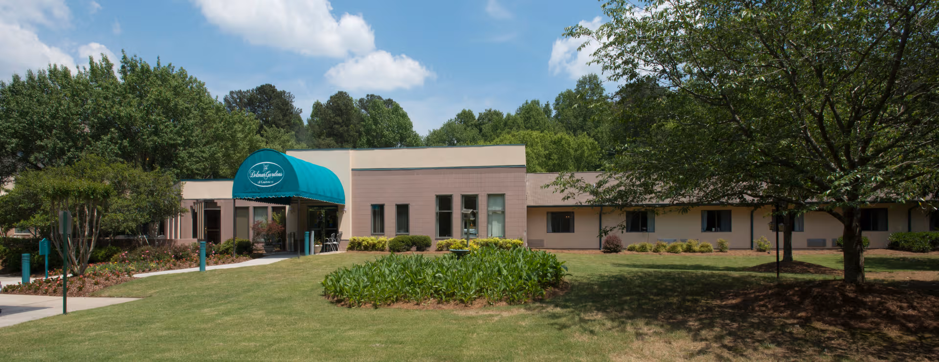 Exterior view of Delmar Gardens of Gwinnett Senior Living entrance with green lawn.