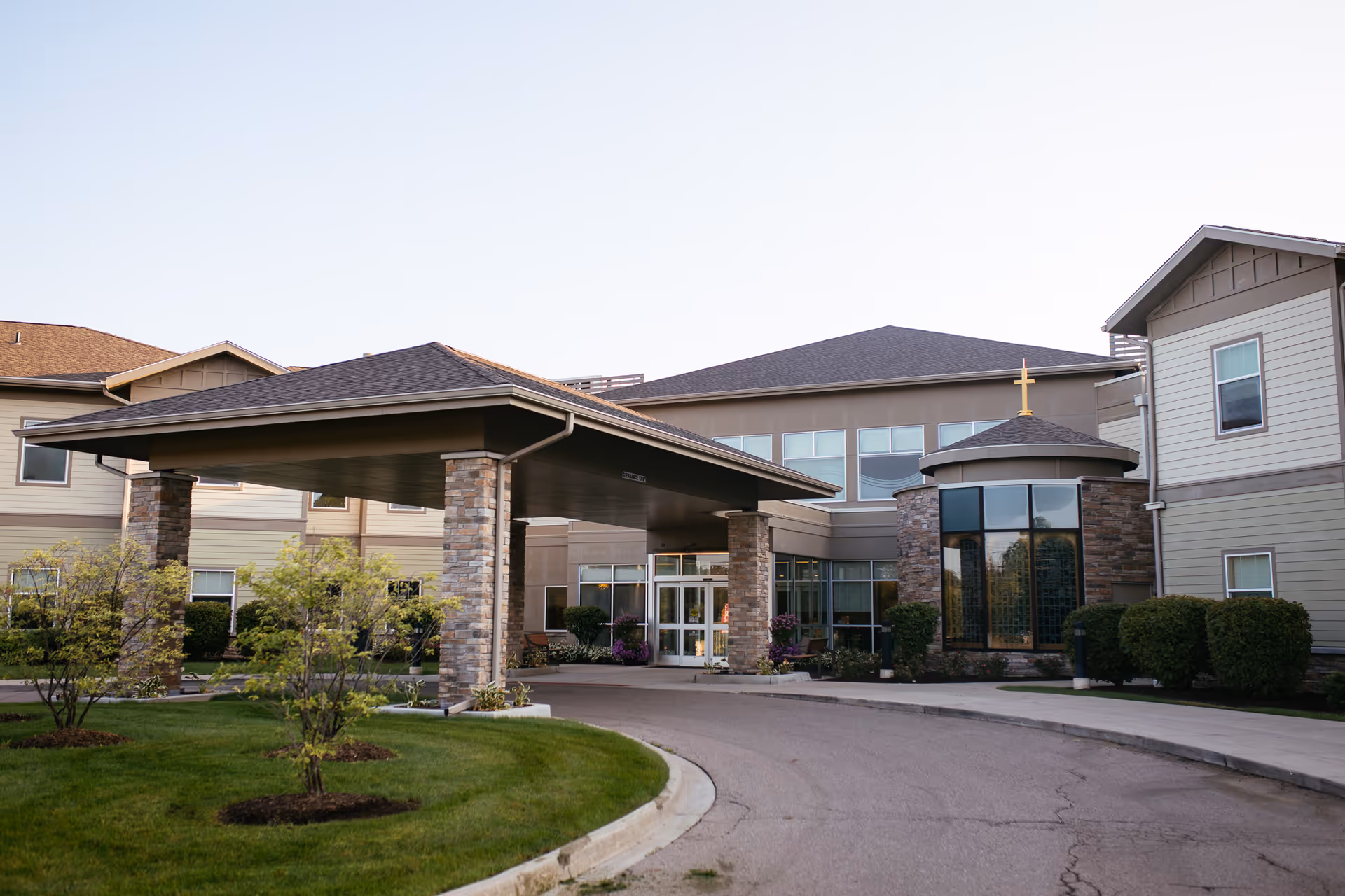 Senior living facility entrance with a covered driveway and stone pillars.