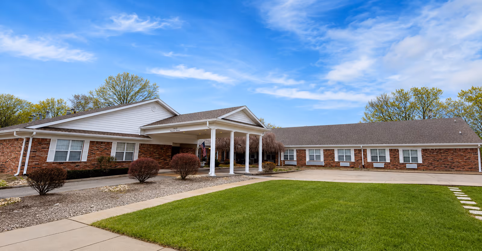 Single-story brick senior living facility with a covered entrance and manicured lawn.