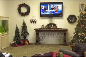 Holiday-themed living room with wreaths, trees, and a wall-mounted TV.