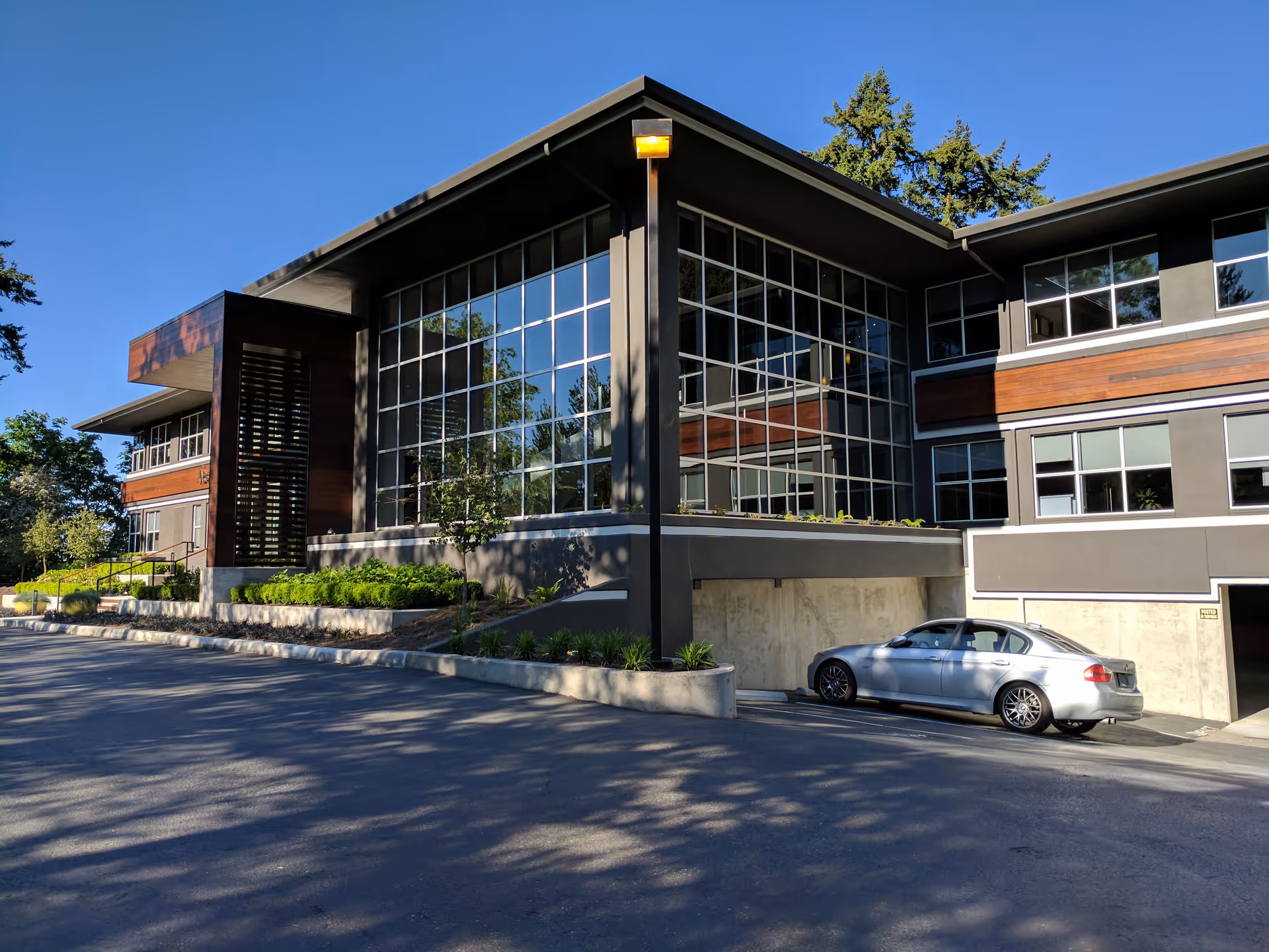 Modern senior living facility exterior with glass walls and a parked silver car.