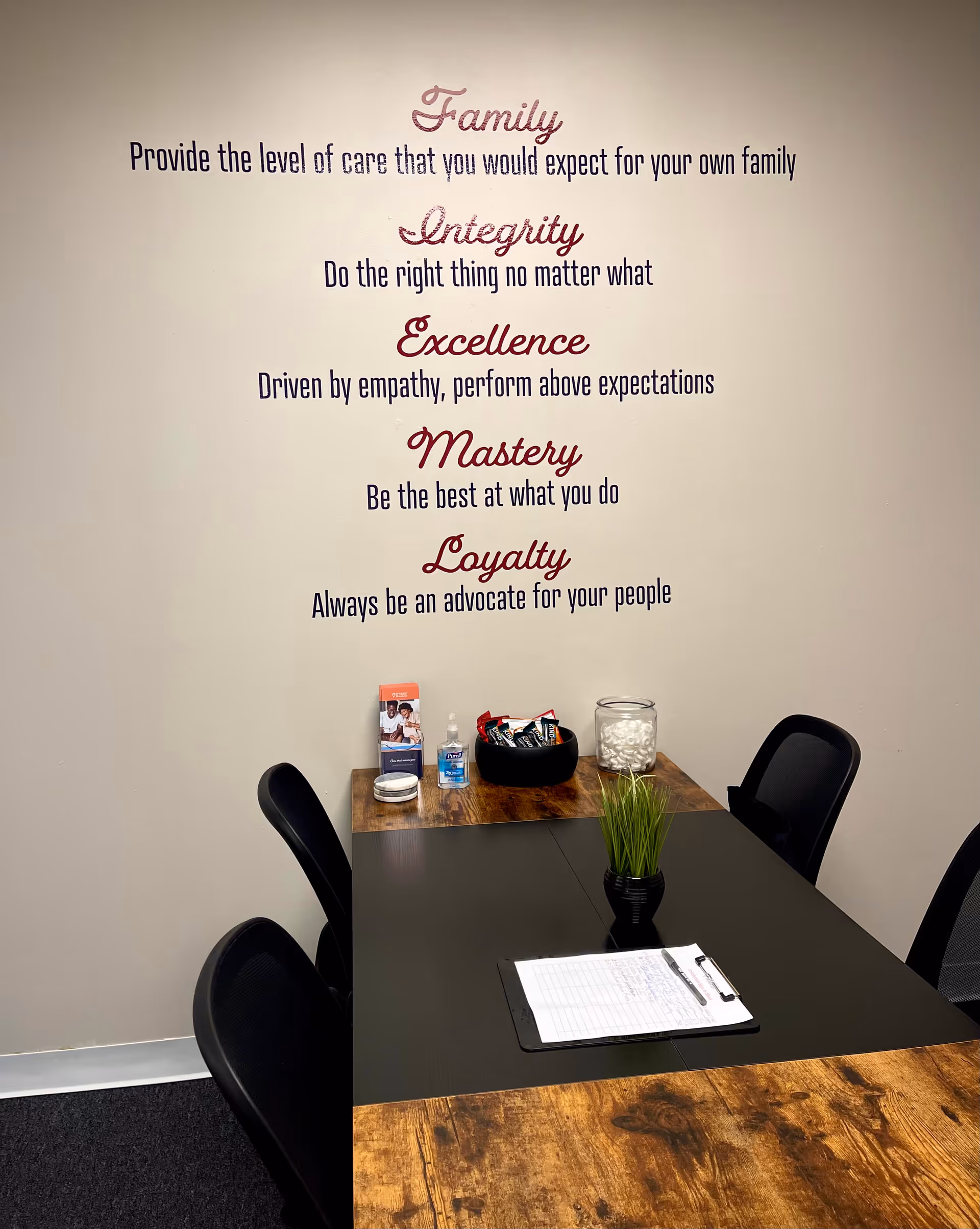 Interior meeting area with a table, chairs, and motivational wall text.