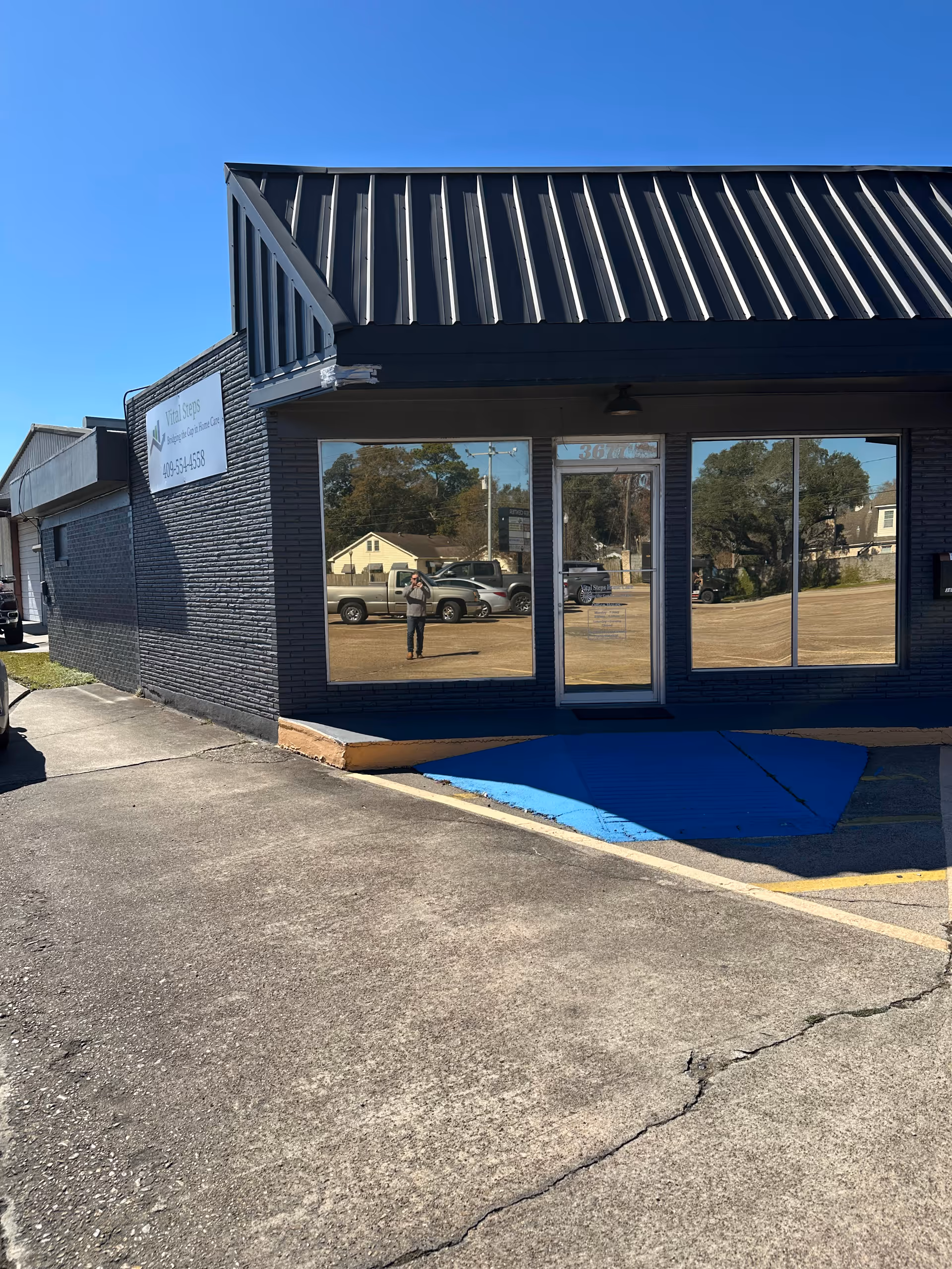 Exterior view of Vital Steps Home Care storefront with blue ramp and parking lot.