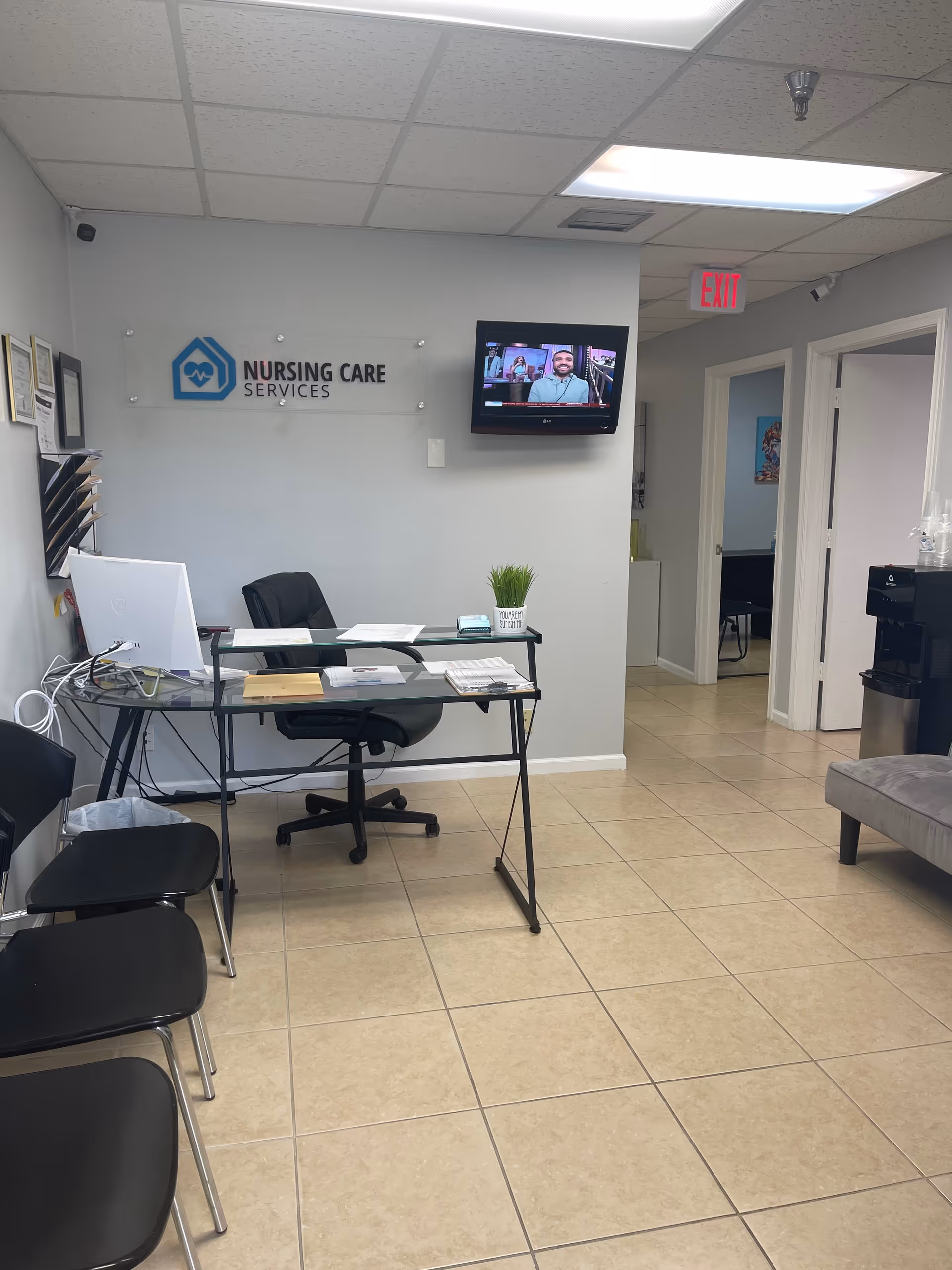 Reception area with desk, chairs, plant, wall sign reading Nursing Care Services.