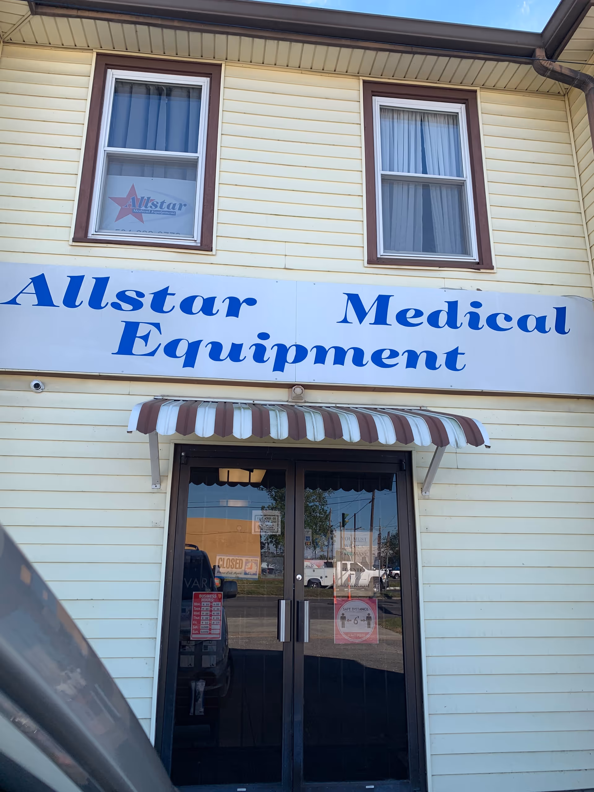 Yellow building facade with Allstar Medical Equipment sign and glass doors.