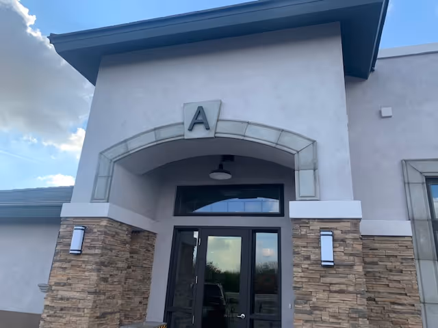 Exterior view of a senior living facility entrance with an arched canopy.