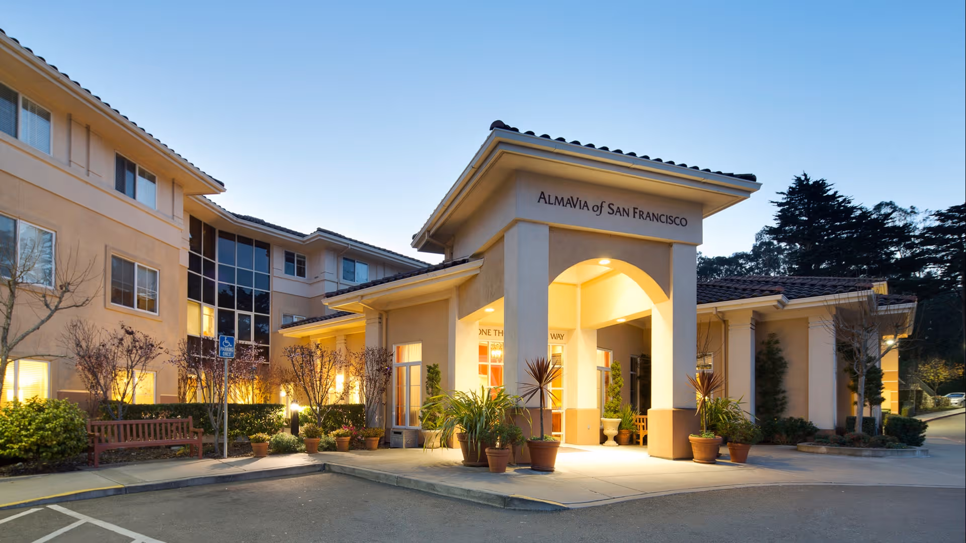 Front entrance of AlmaVia of San Francisco with potted plants and warm lighting.