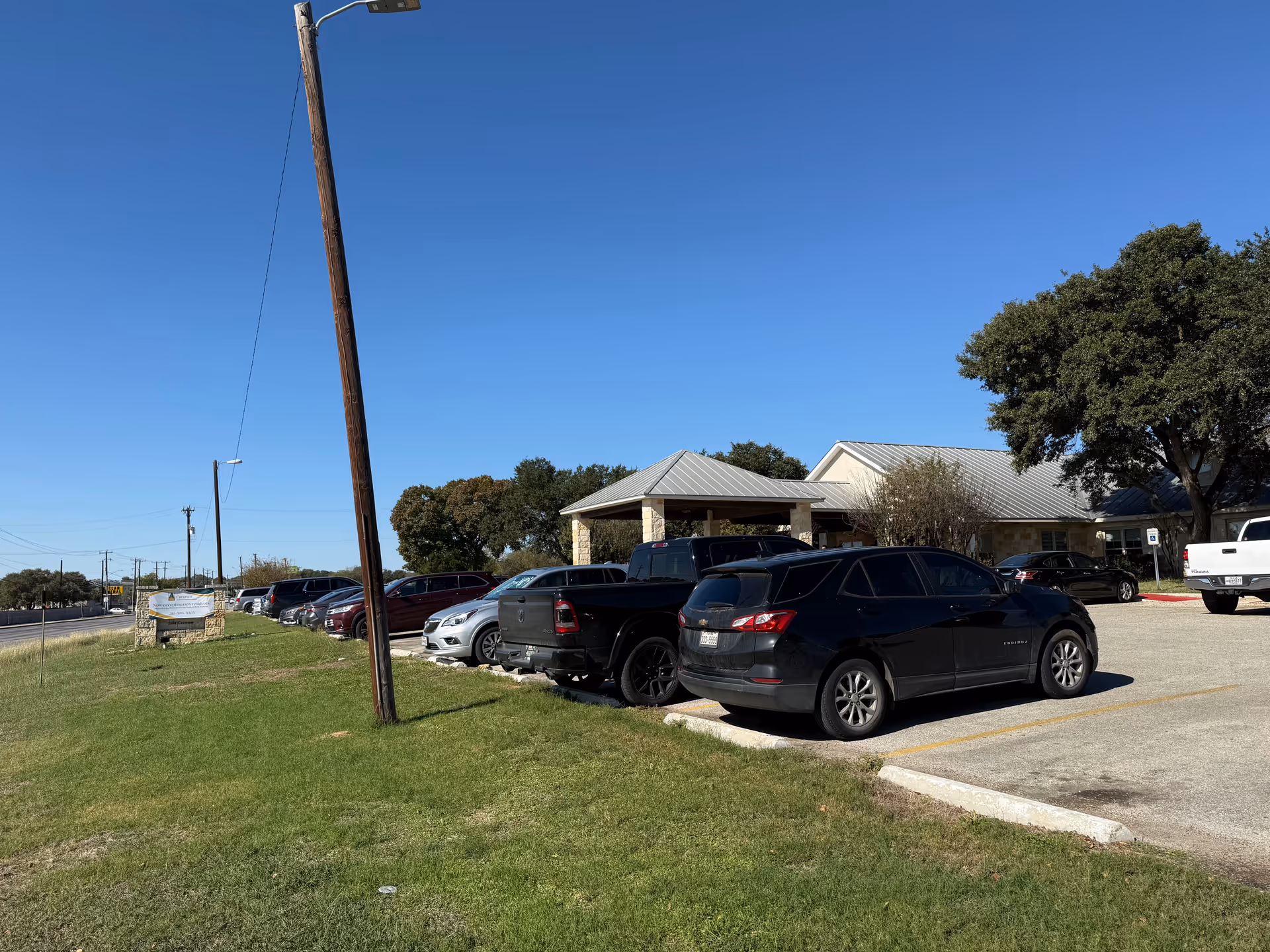 Parking lot with multiple cars in front of Meridian Care facility under clear blue sky