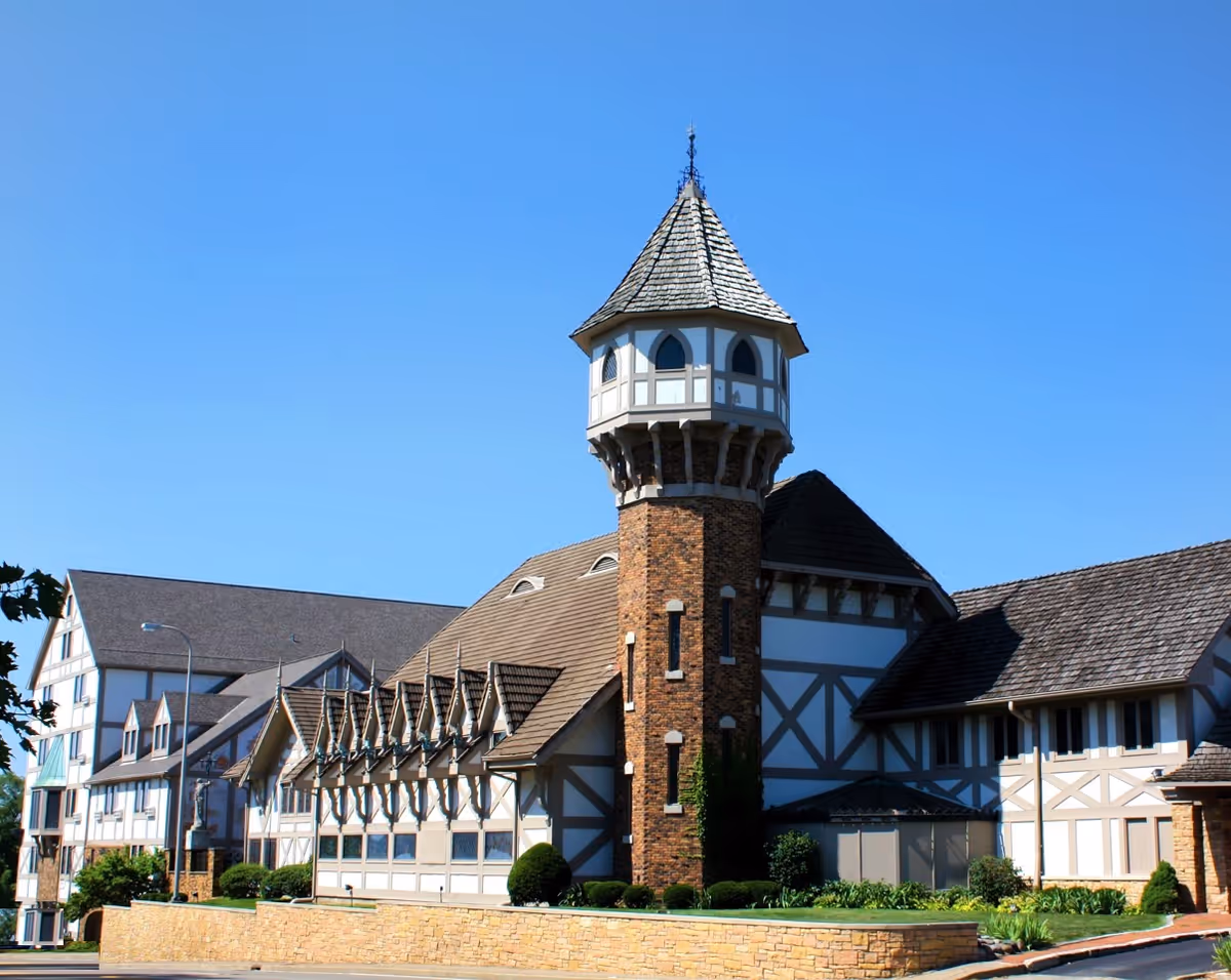 Exterior view of a castle-style senior living facility with a tall turret and brick facade.