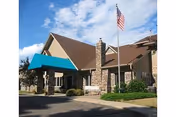 Town Village senior living facility exterior with brick entrance, flag, and turquoise awning.