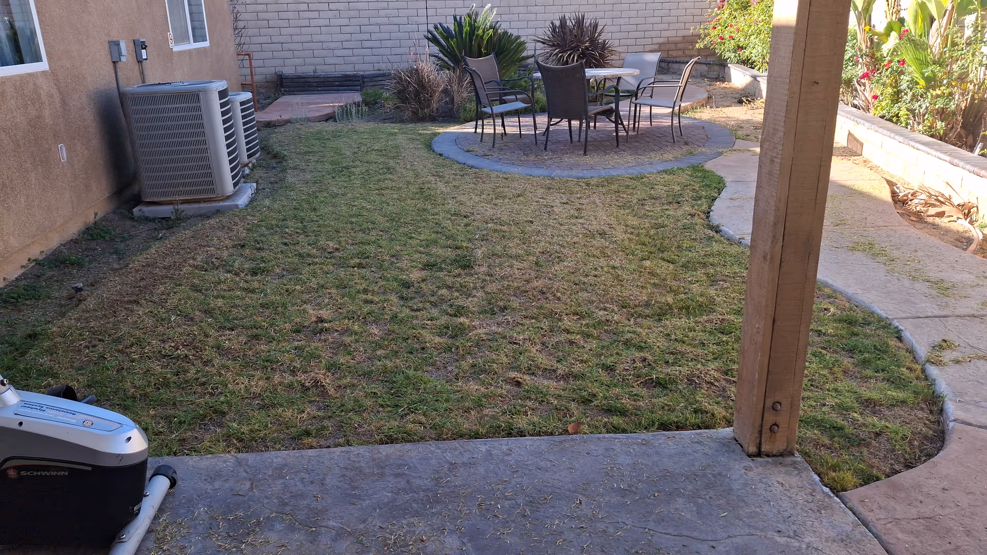 Outdoor patio area with a circular stone seating area and surrounding lawn near a building.