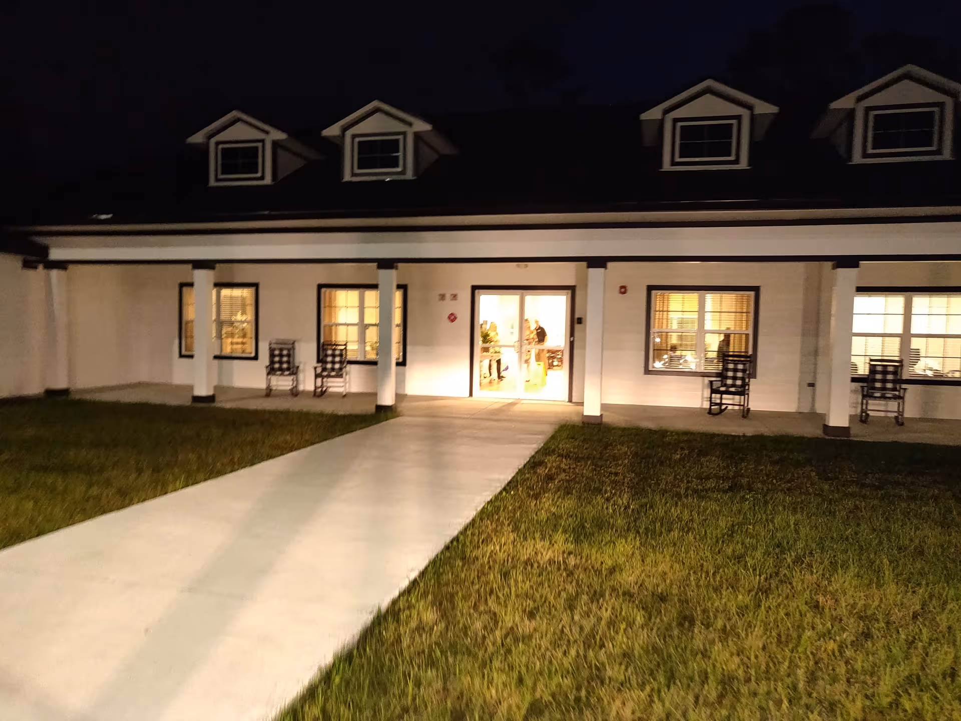 Night exterior of Silver Treasures at Ponte Vedra with illuminated entrance and chairs outside.