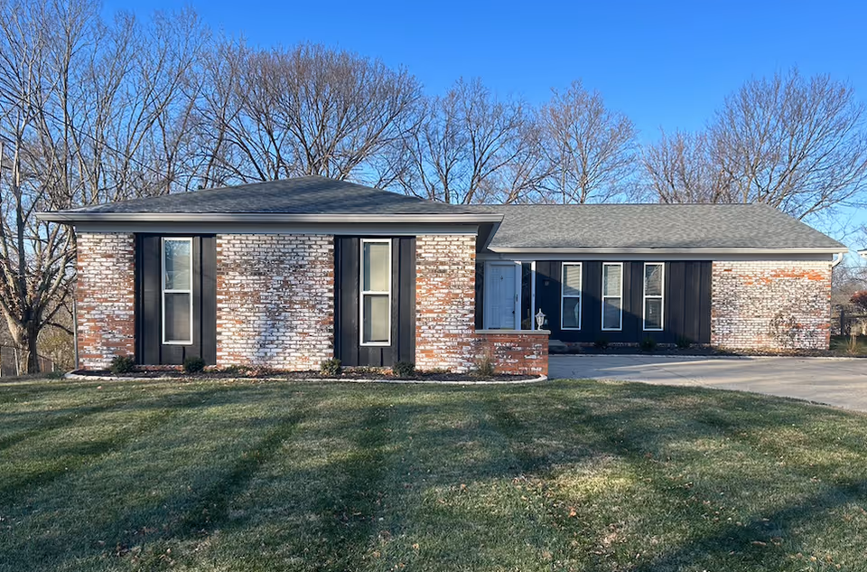 Single-story brick senior living facility with a curved driveway and bare trees in background.