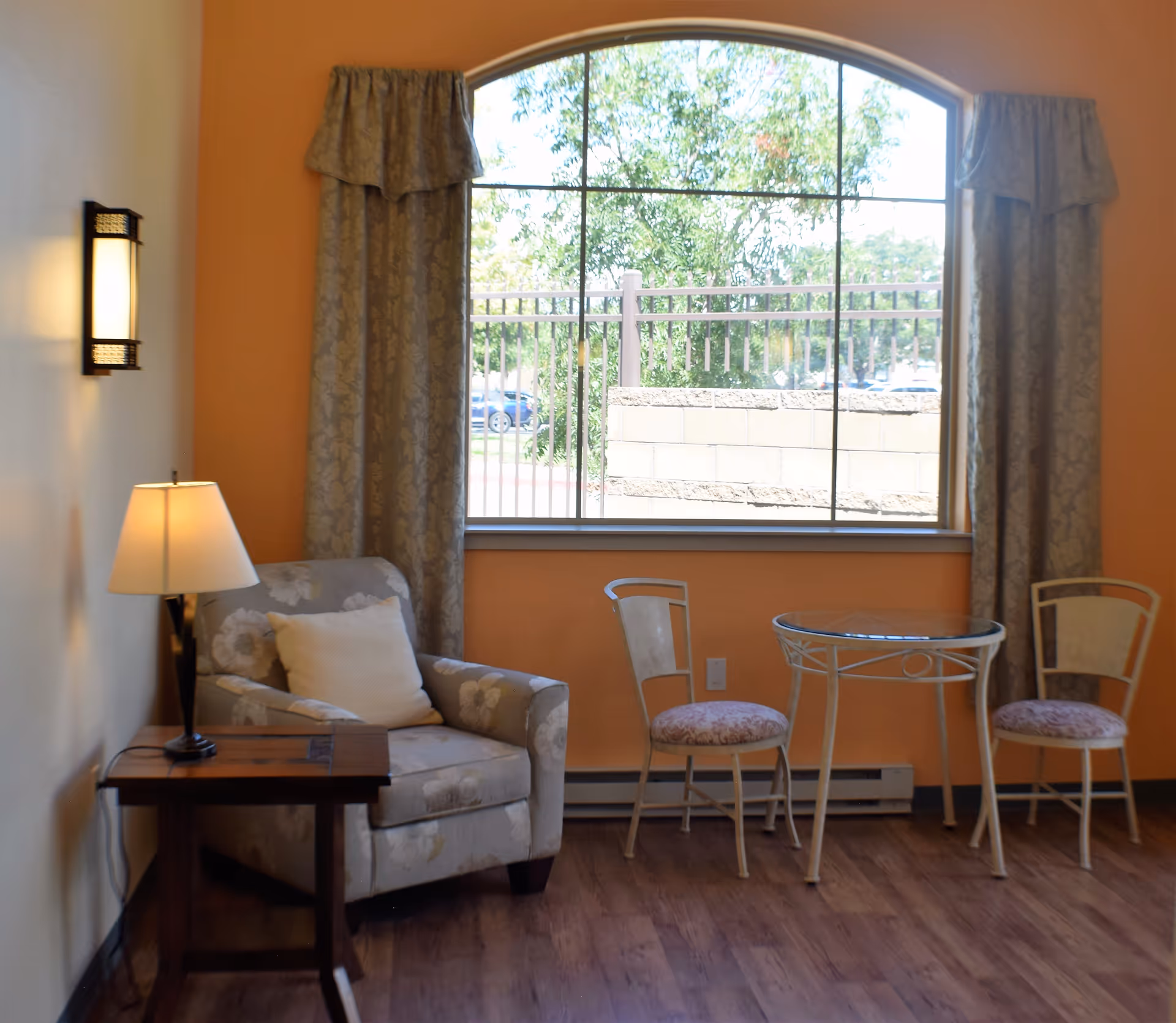 Cozy seating area with an armchair, loveseat, lamp, and large window.