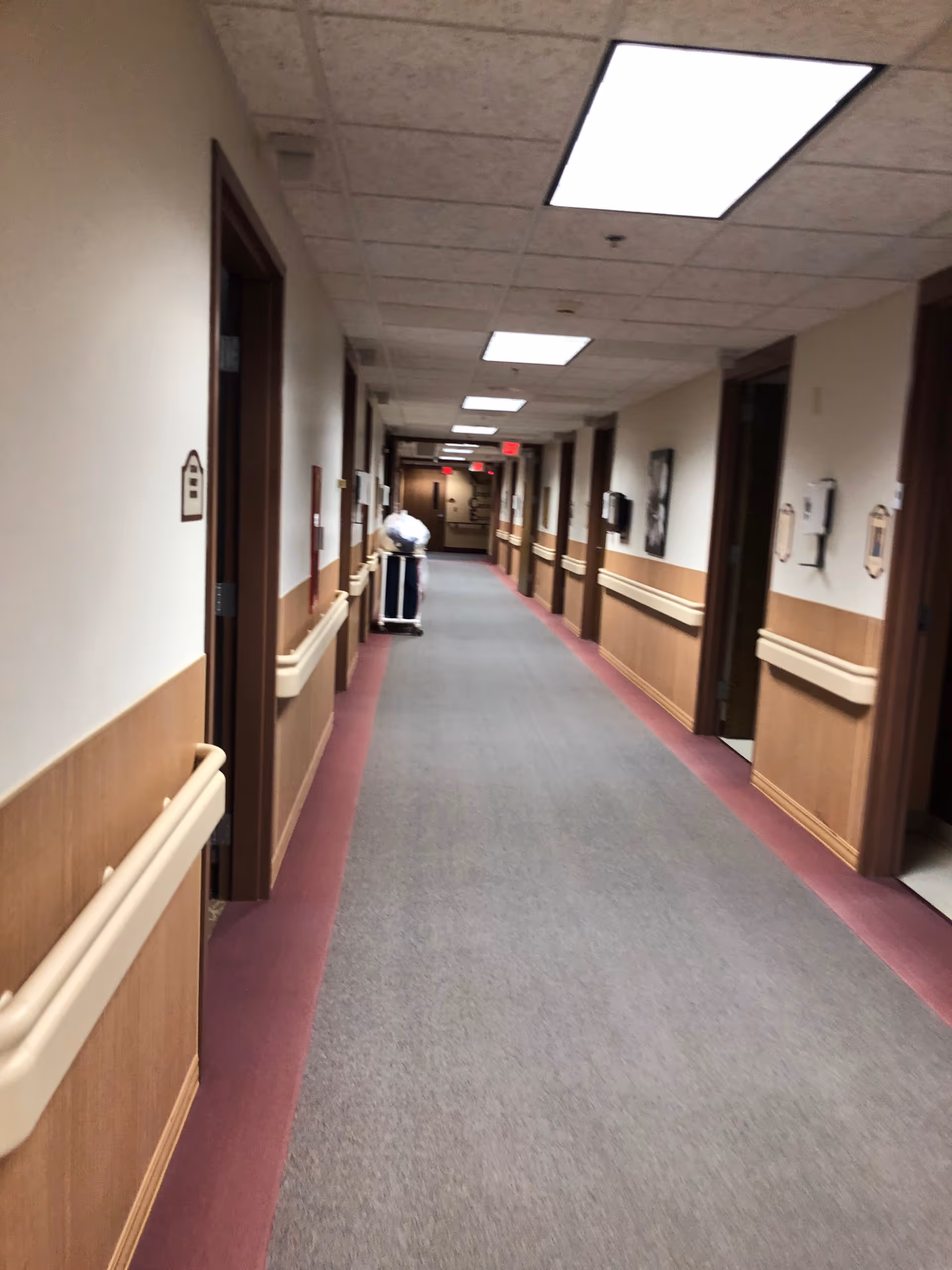 Long hallway in a senior living facility with doors and handrails.