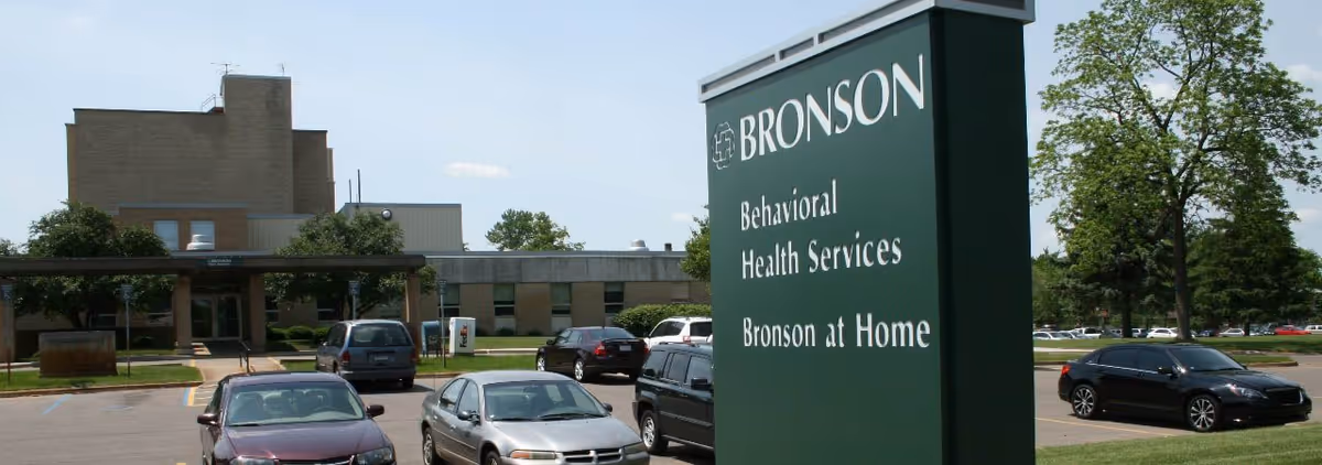 Exterior view of Bronson at Home facility with green sign and parking lot.