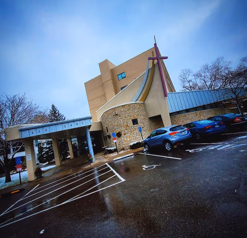 Exterior view of the Cerenity Senior Care building with a stone entrance and parking.