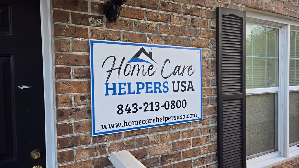 Brick exterior wall with a Home Care Helpers USA sign beside a window.
