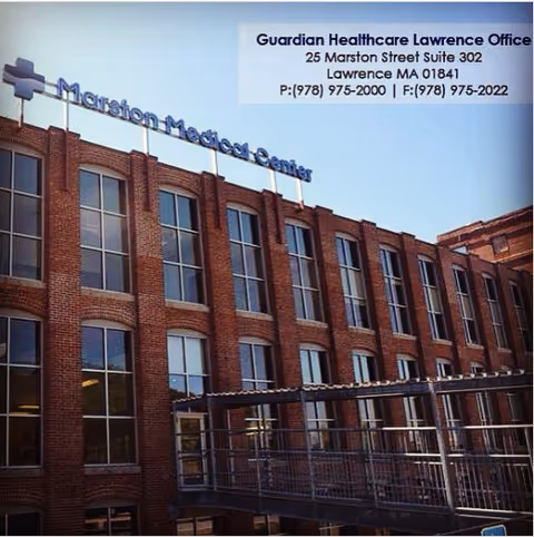 Exterior view of a brick Guardian Healthcare building with signage and many windows.