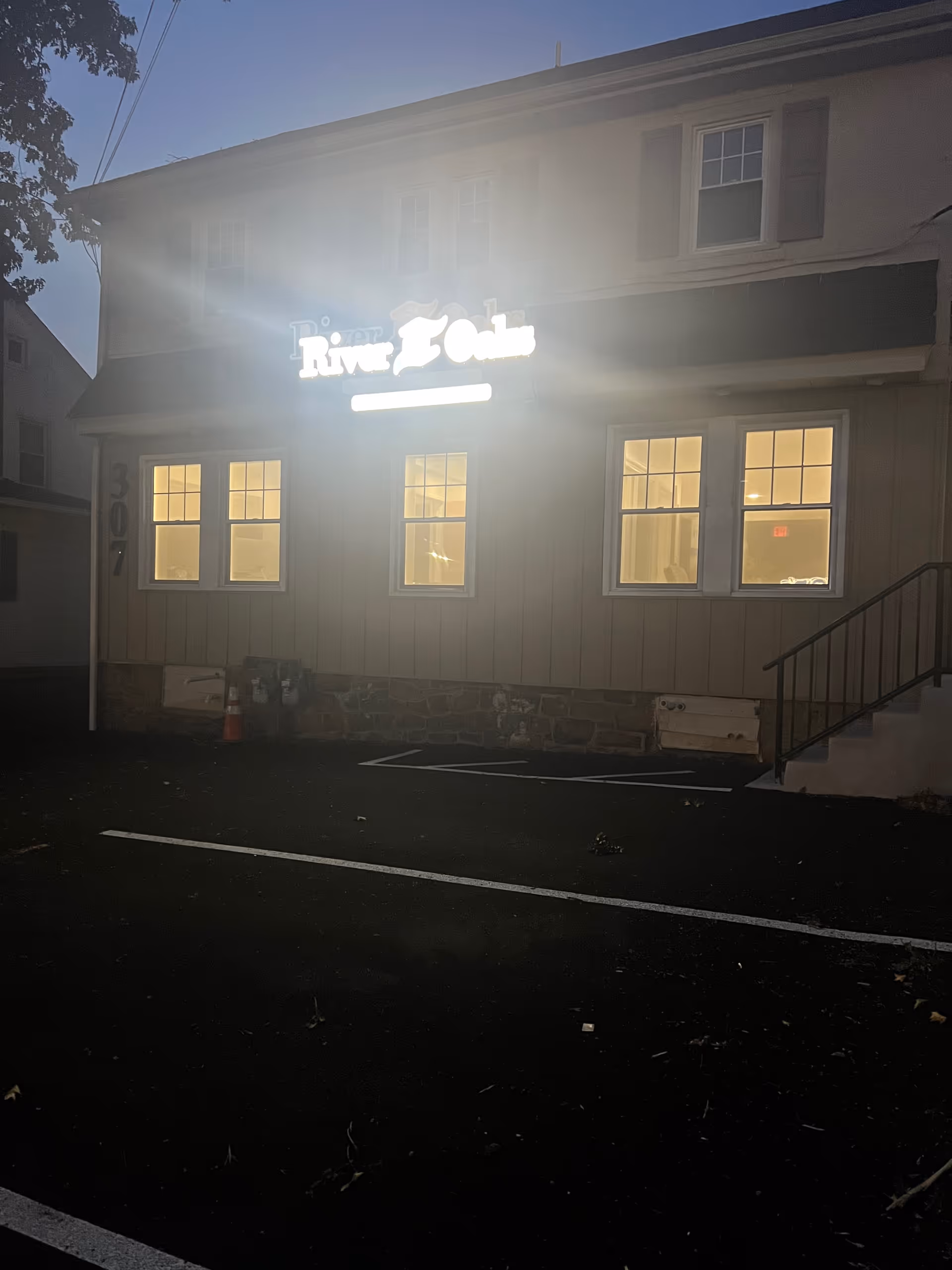 Front of River Oaks Home Care building with glowing sign and lit windows at dusk.