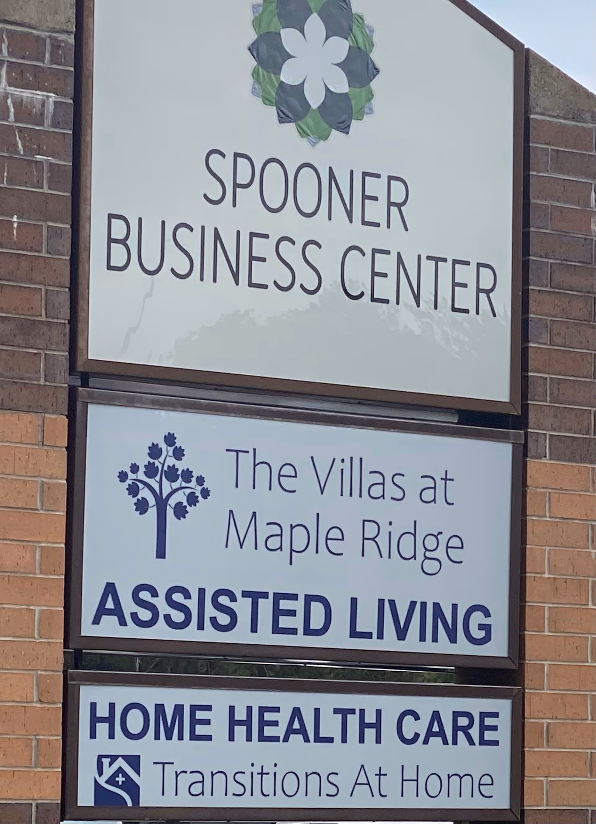 Exterior brick signs advertise Spooner Business Center and The Villas at Maple Ridge Assisted Living