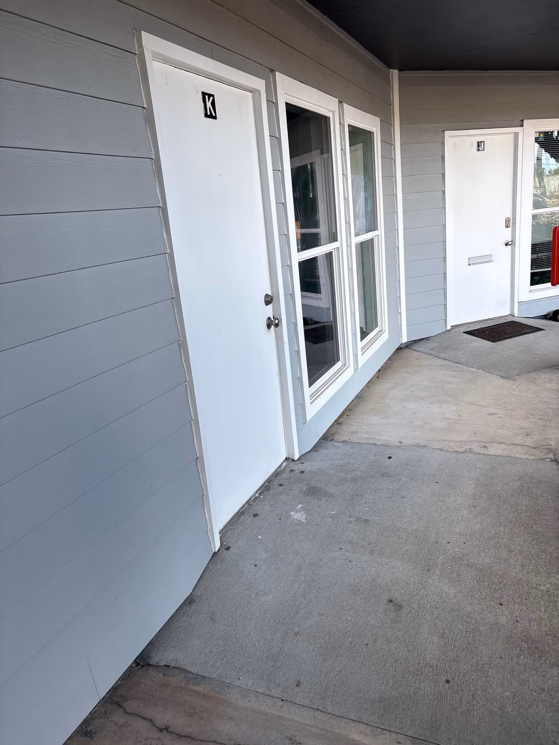 Exterior walkway of a senior living building with white doors and windows.