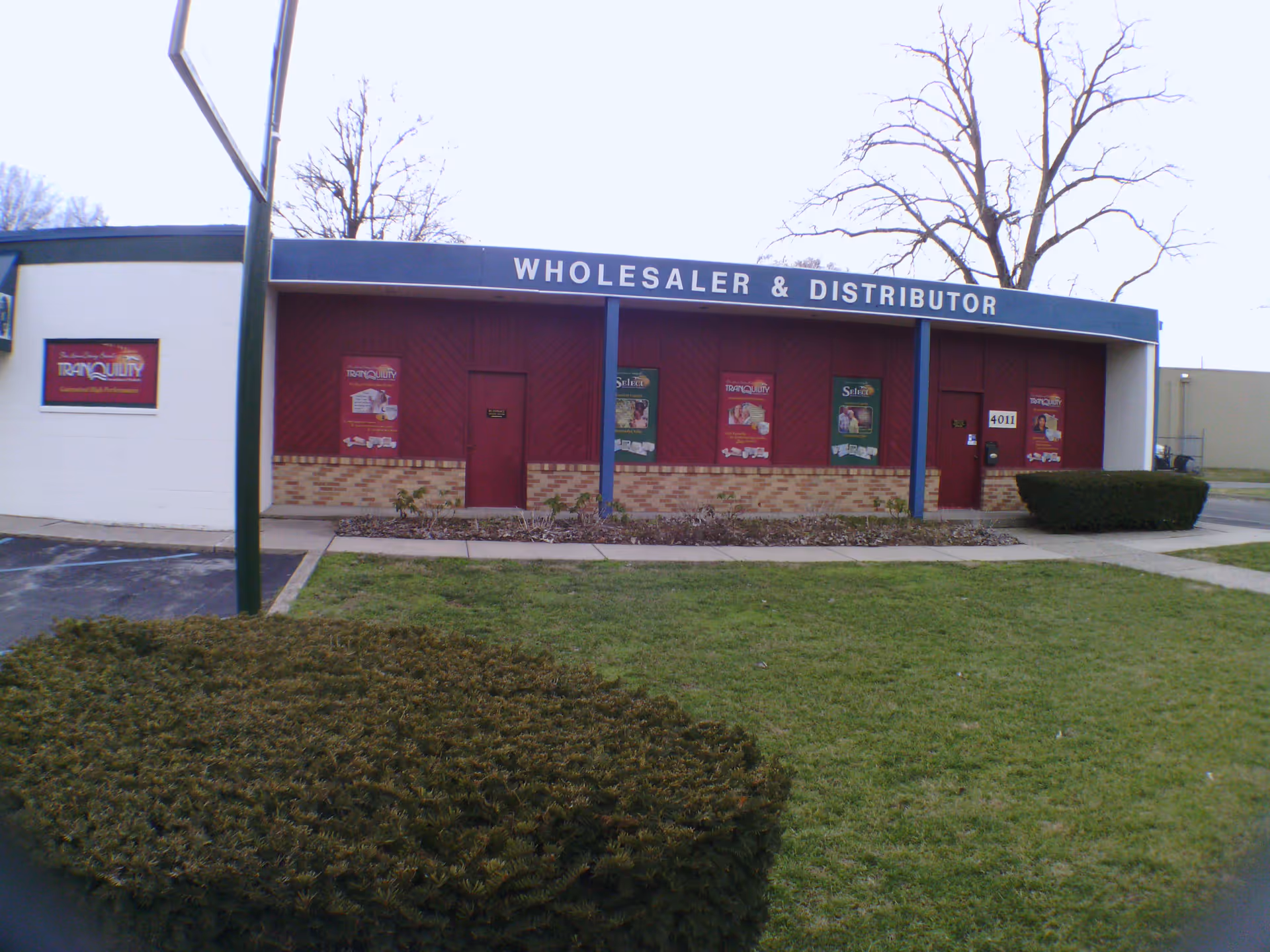 Exterior view of a building labeled Wholesaler and Distributor with red doors and brick base.