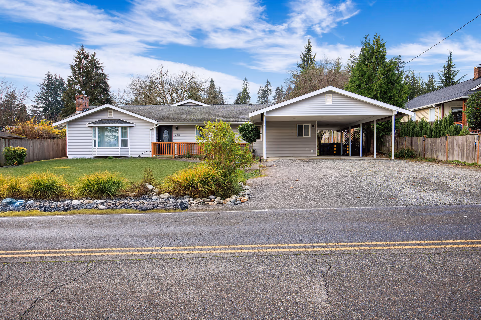 Exterior view of a single-story adult family home with a front yard and carport.
