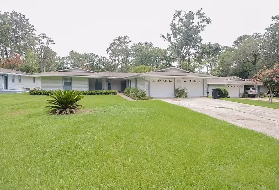 Single-story villa-style homes with attached garages along a grassy front yard.