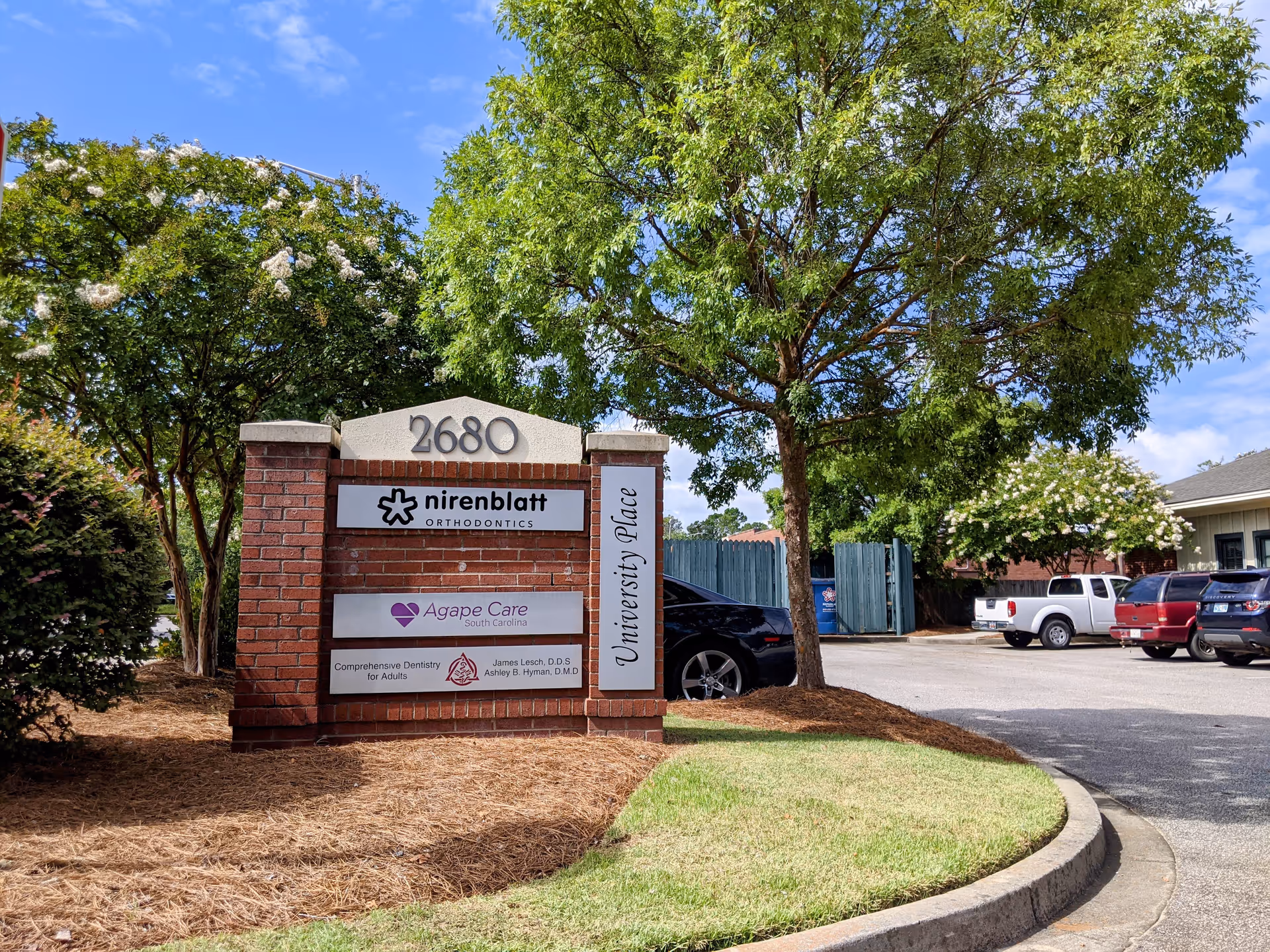 Brick entrance sign with Agape Care and University Place signage at a parking lot.