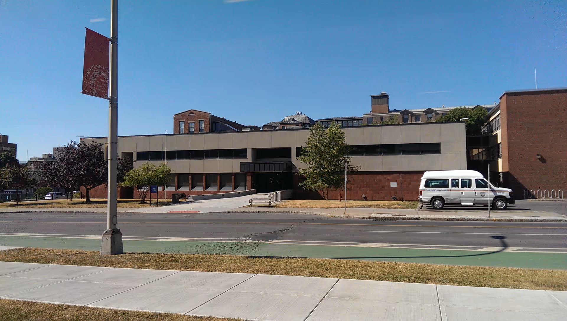 View of Health Services facility exterior with a sidewalk, road, and a white van.