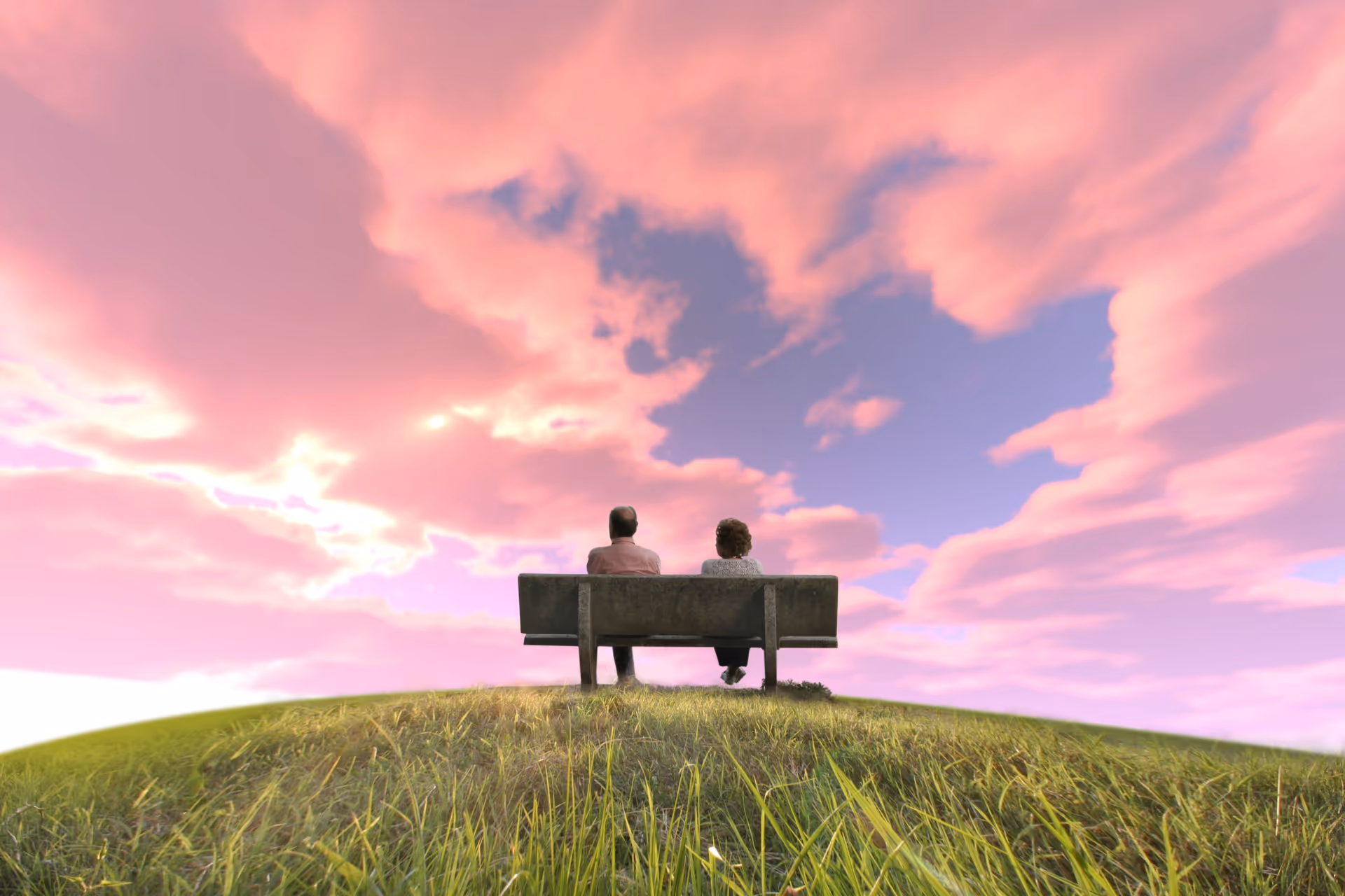Two people sit on a bench on a grassy hill under a pink sunset sky.