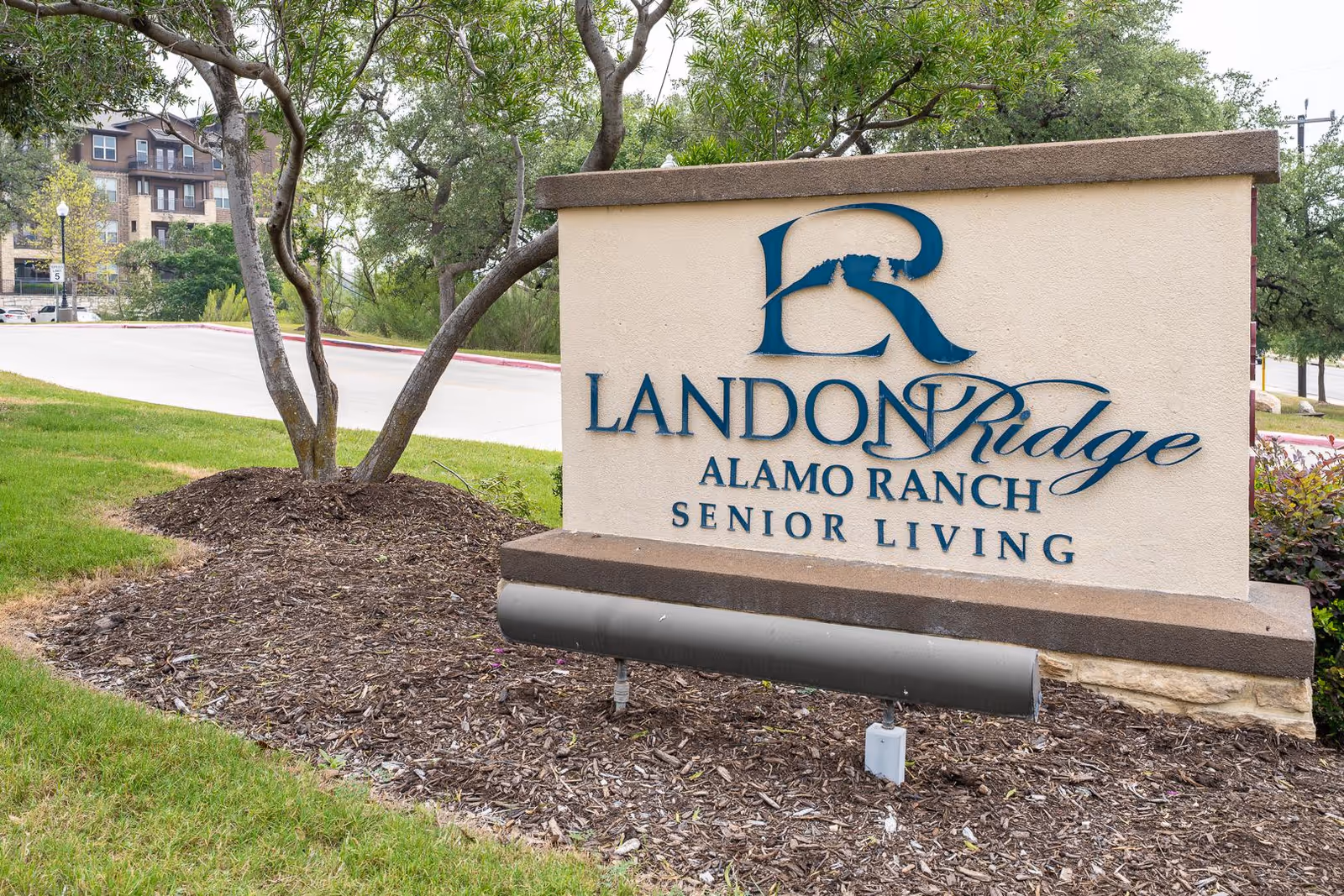 Exterior sign for Landon Ridge Alamo Ranch Senior Living with trees and landscaping.