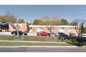 Towne Manor West exterior: a brick, single-story building with parked cars and trees.