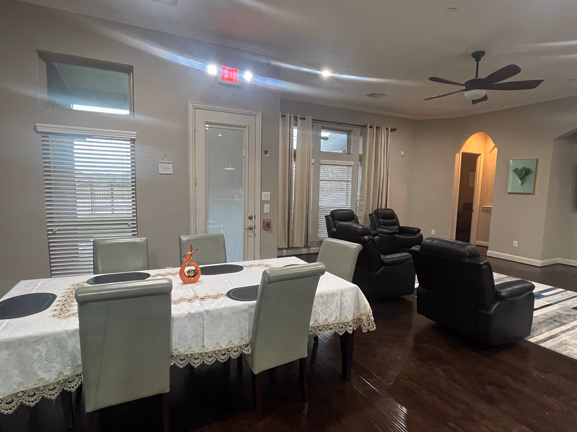Dining room with a long table, lace tablecloth, and multiple recliner chairs nearby.