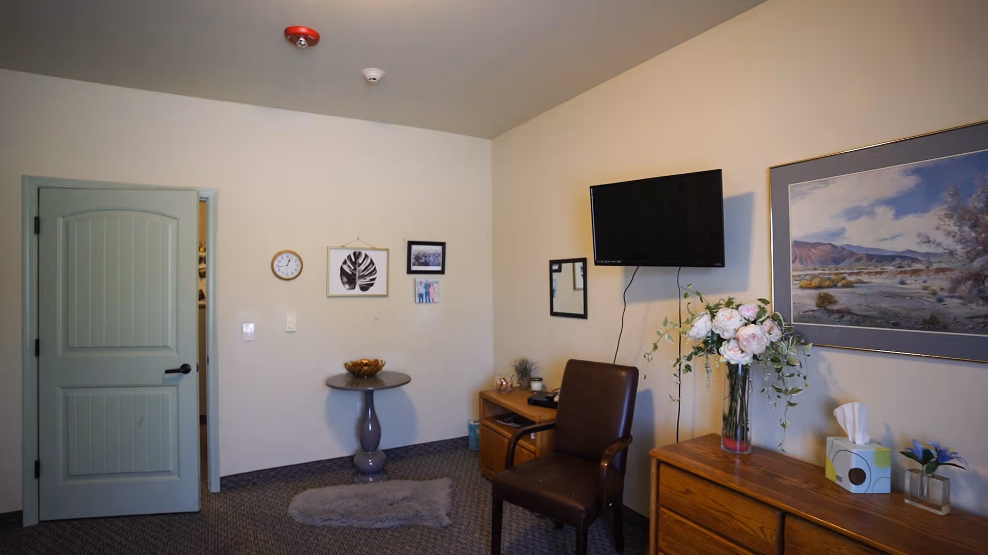 Common living area with chair, television, wall art, and a floral arrangement.