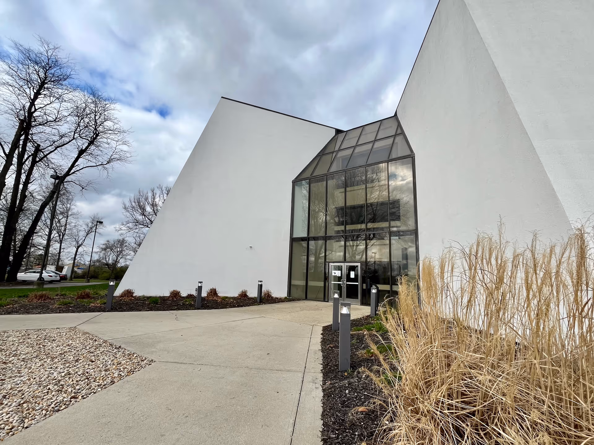 Exterior view of a modern building with a glass entrance and concrete walkway.
