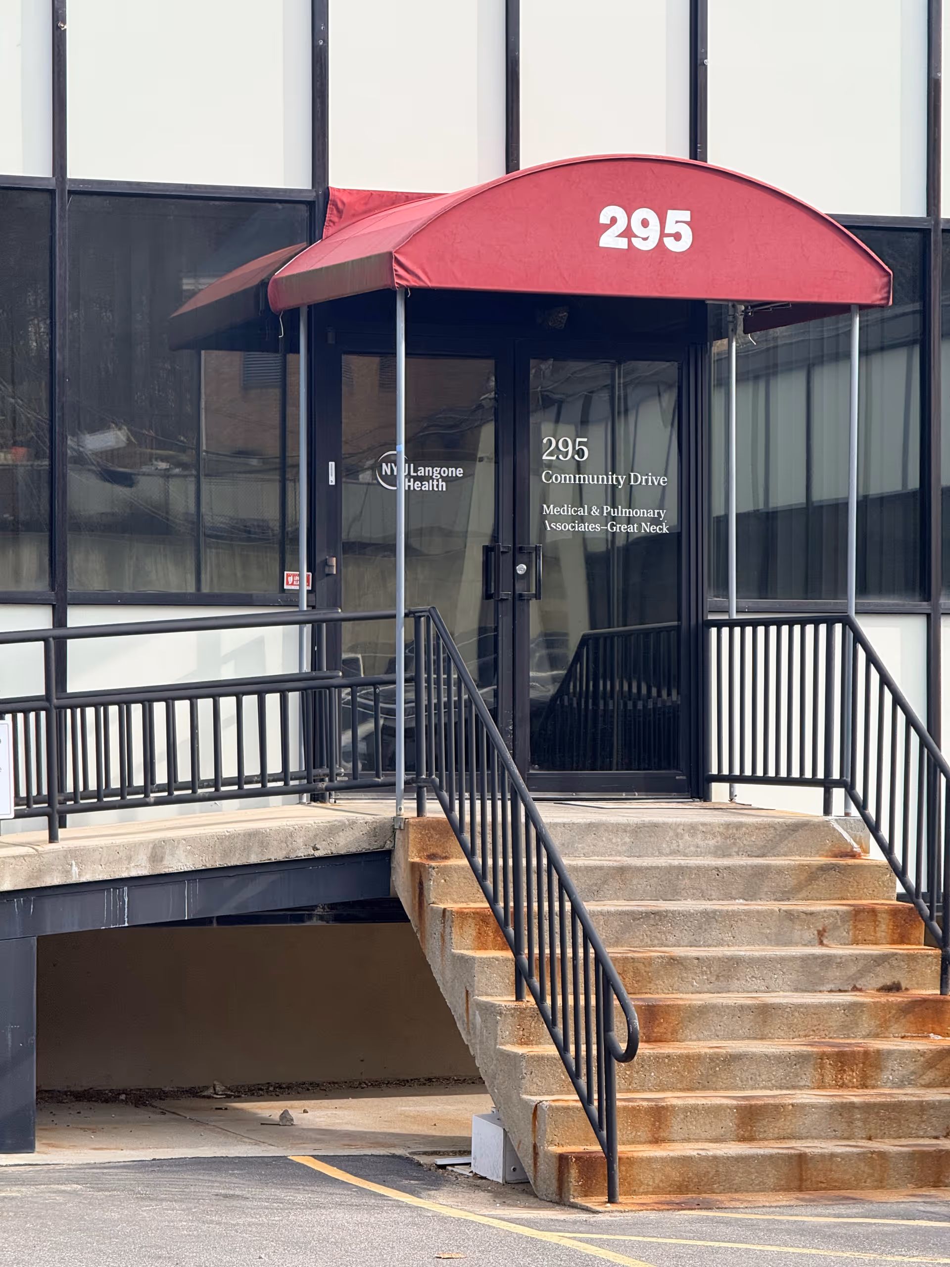 Exterior building entrance with a red canopy labeled 295 and glass doors.