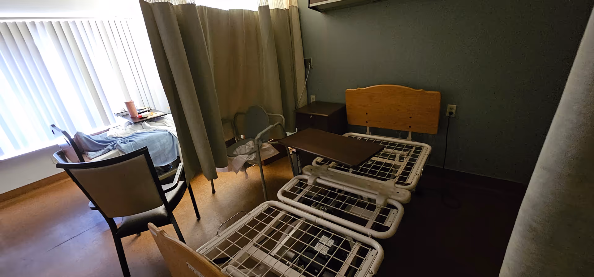Shared patient room at Foothills Rehabilitation Center with beds, chairs, and privacy curtains.