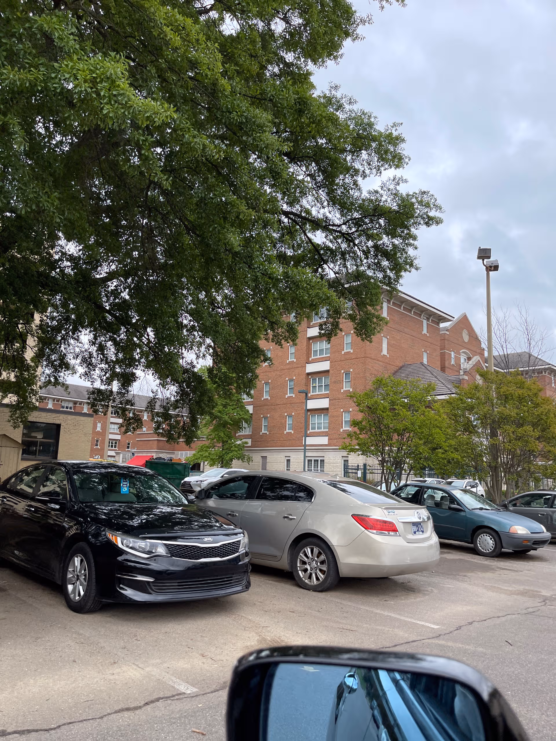 Exterior view of a brick senior living building with a parking lot and trees.