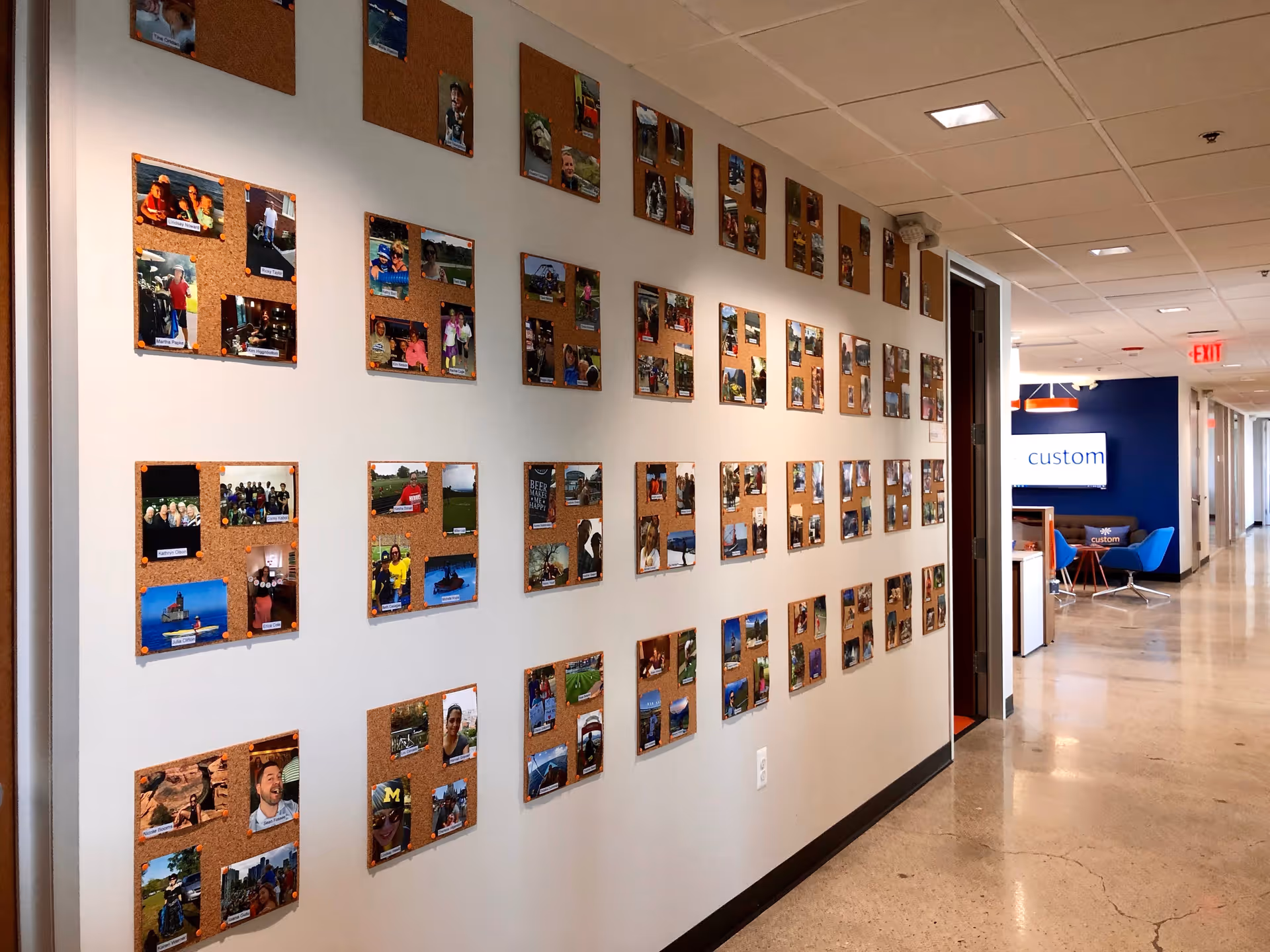 Interior hallway lined with corkboard photo displays along the wall and a seating area ahead.
