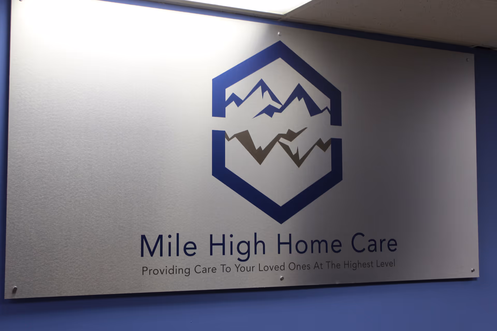 Interior wall displays Mile High Home Care sign with blue mountain logo and slogan.