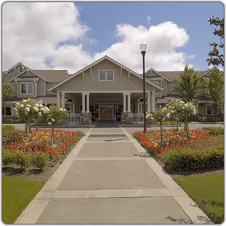 Front exterior view of a senior living facility with a central entrance and landscaped grounds.