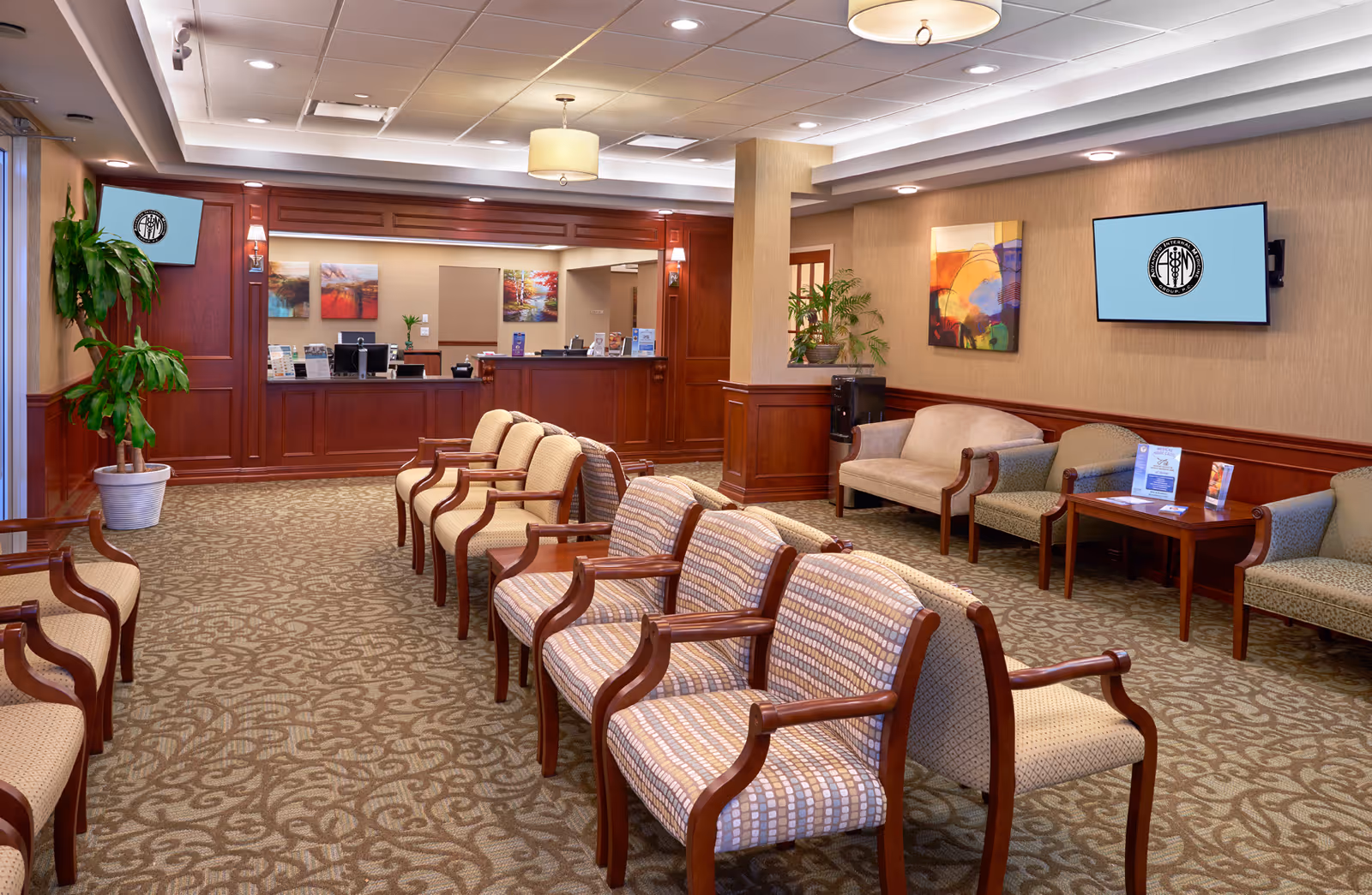 Spacious, wood-paneled lobby with a long reception desk, rows of cushioned chairs, and wall art.
