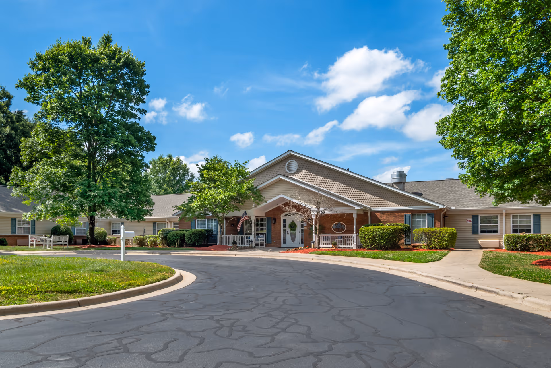 Brookdale South Park exterior building with entrance, curved driveway, and landscaped trees.