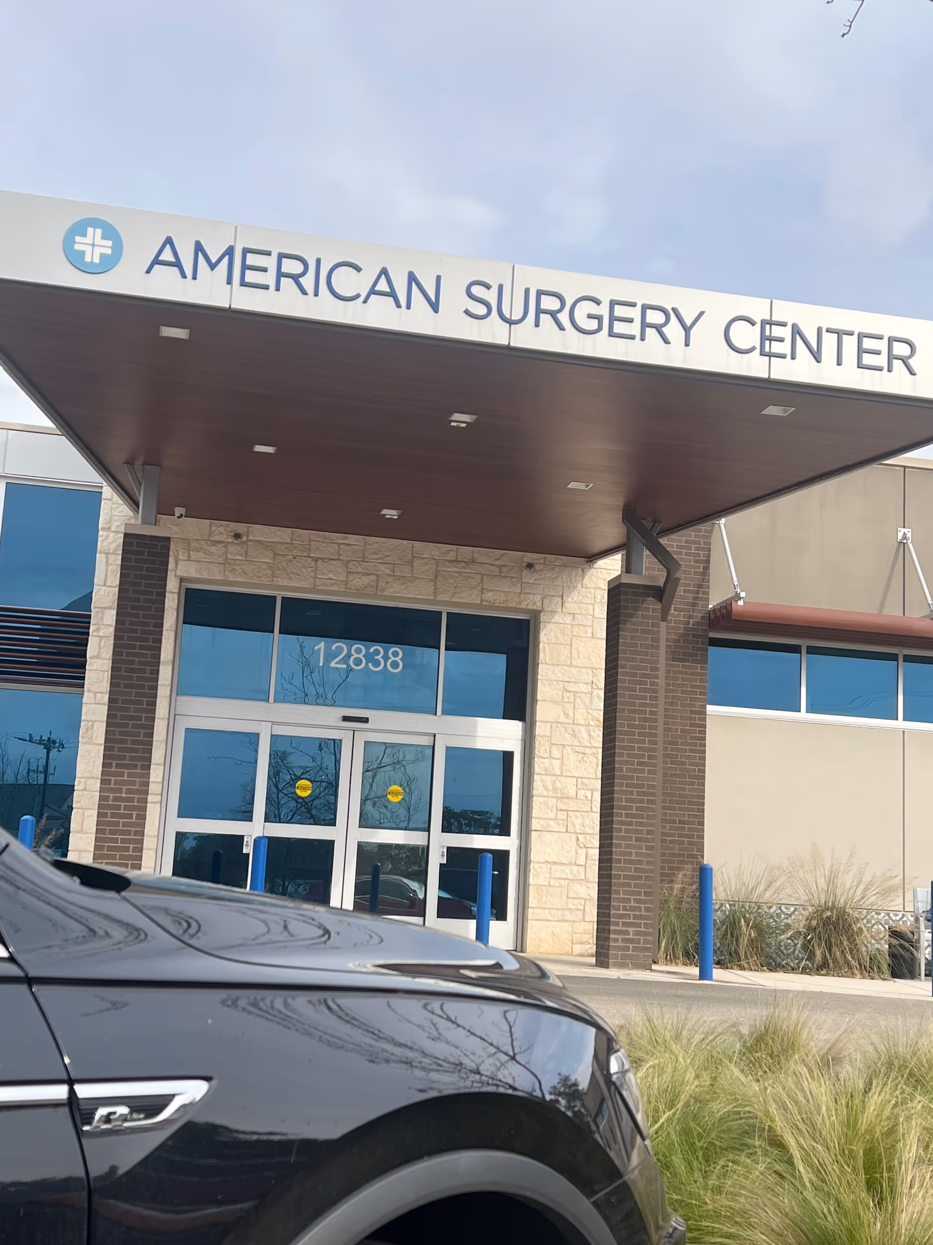 Exterior view of the American Surgery Center front entrance with glass doors and signage.