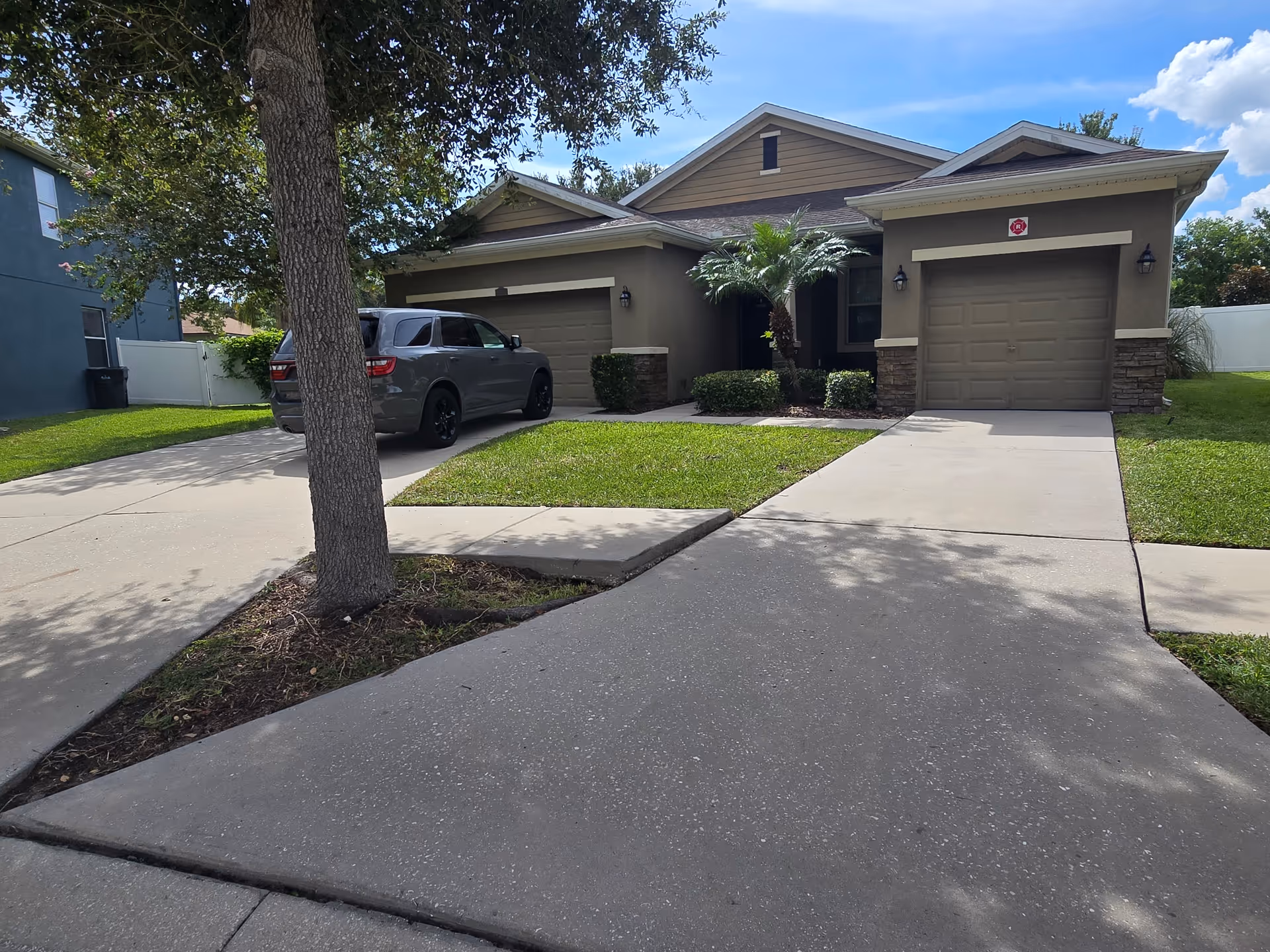Front exterior view of a tan, two-car garage home with a driveway and well-kept lawn.