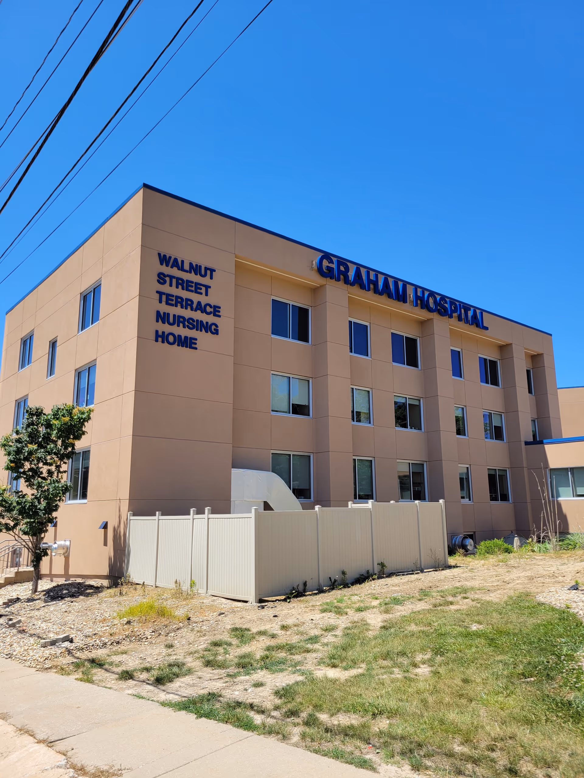 Exterior view of Graham Hospital building with beige walls, windows, and a surrounding yard.